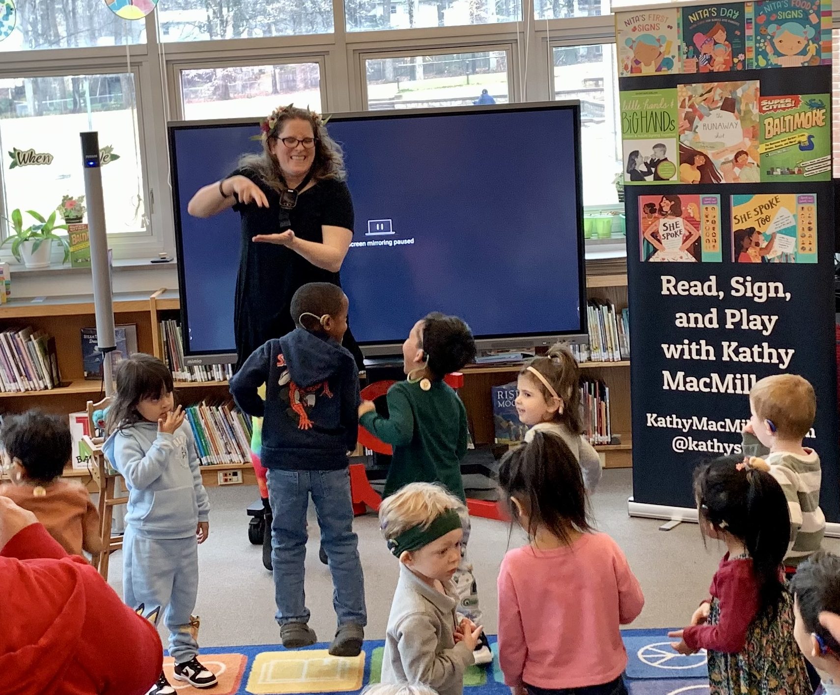 Kathy MacMillan signs JUMP with a group of preschoolers.
